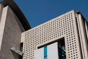 Fachada moderna de prédio com elementos de design que equilibram estética e eficiência, usando perfurações e materiais contemporâneos, ideal para aprender como combinar esses conceitos em projetos arquitetônicos.